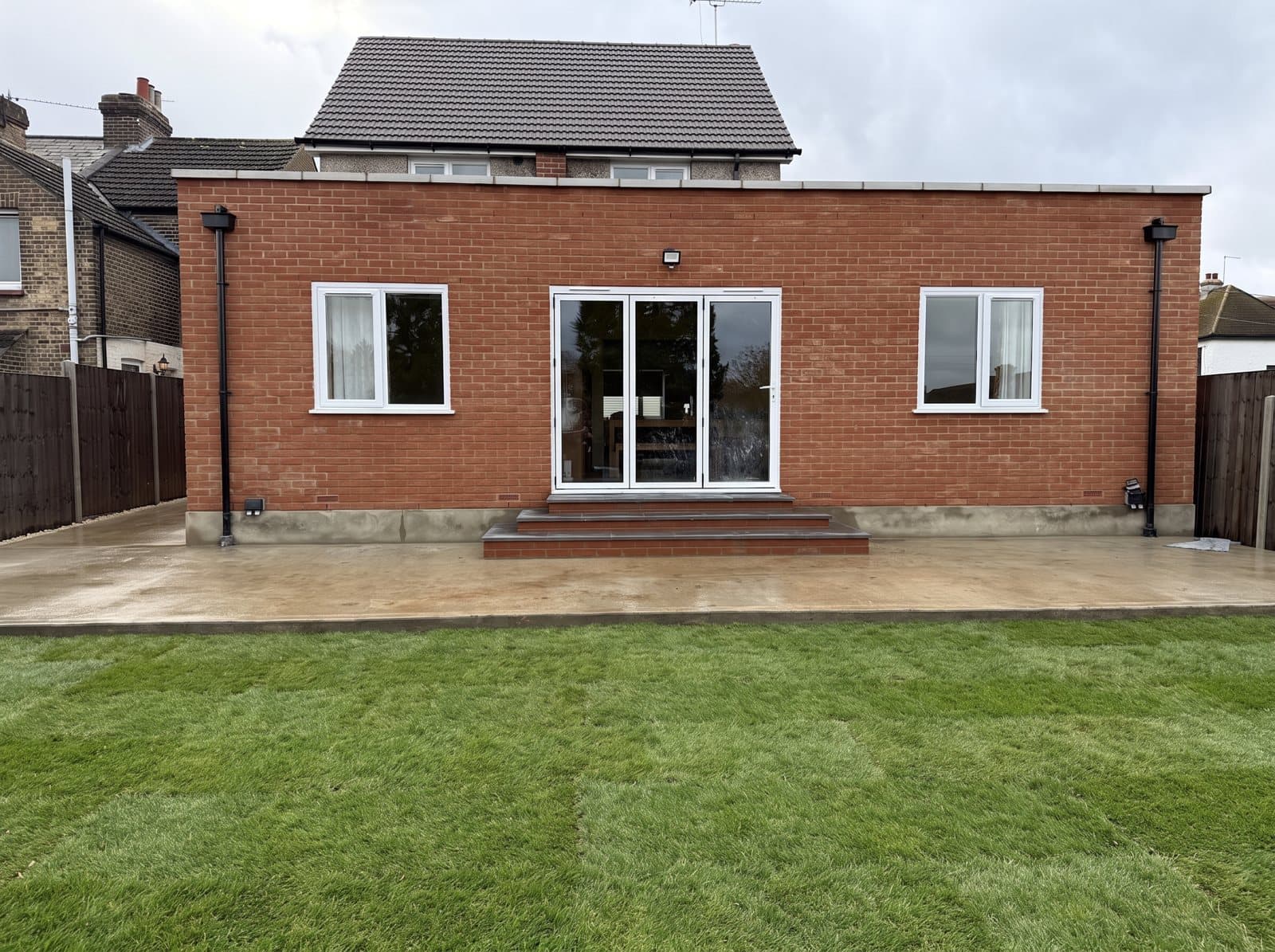 A single-storey red-brick rear extension with sliding doors onto a new lawn