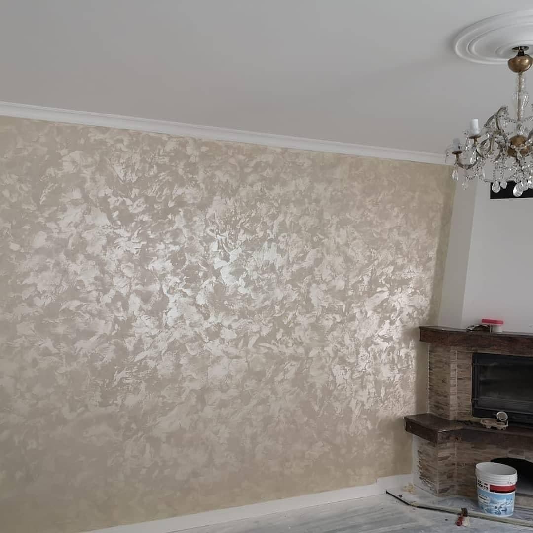 A refurbished room with a gold feature wall, a fireplace and a chandelier