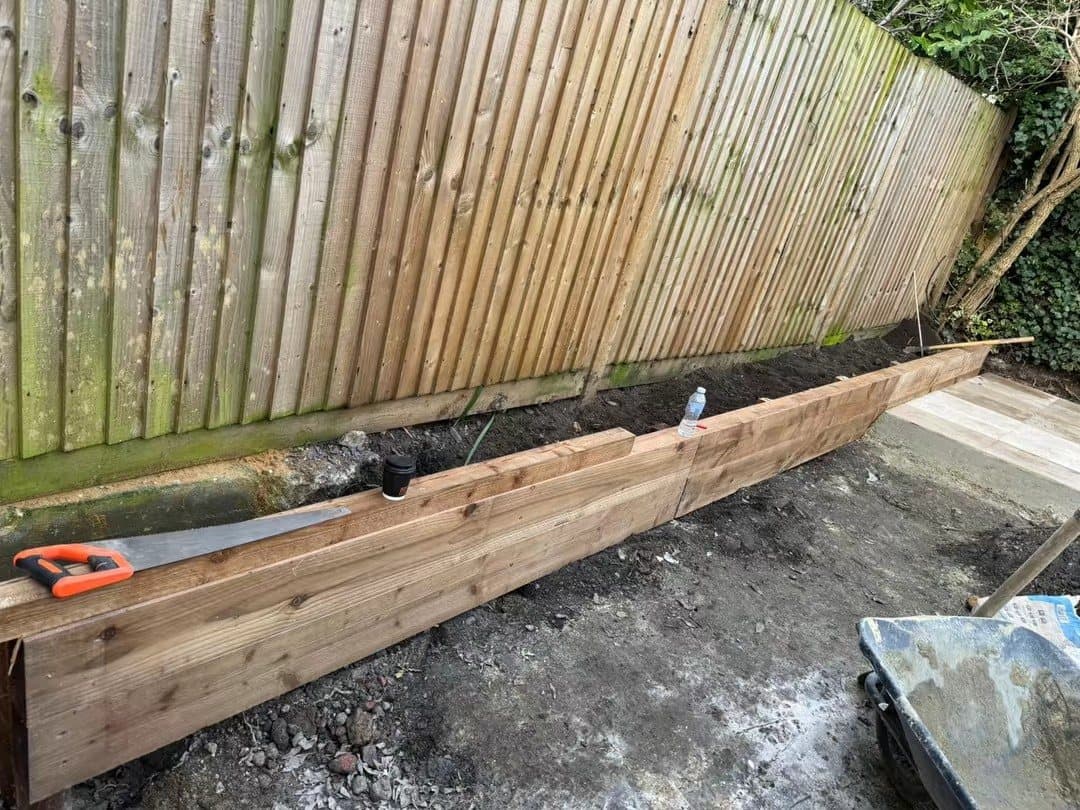 Timber sleepers being set out for raised beds in a cleared garden