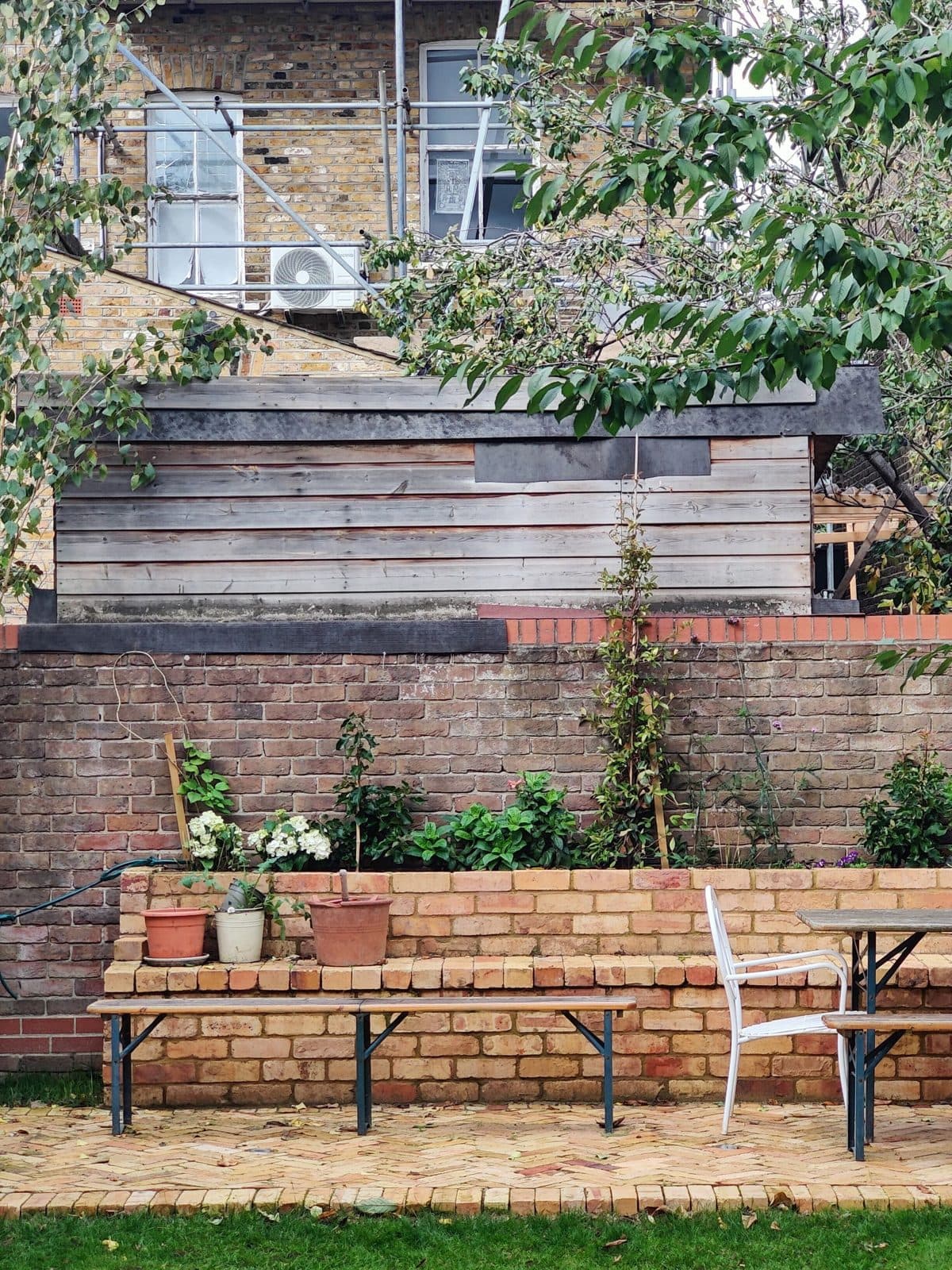 A brick terrace and garden wall with a bench