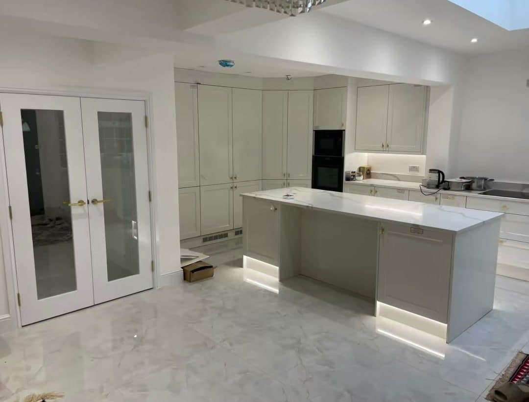 An open-plan kitchen with a white island and French doors