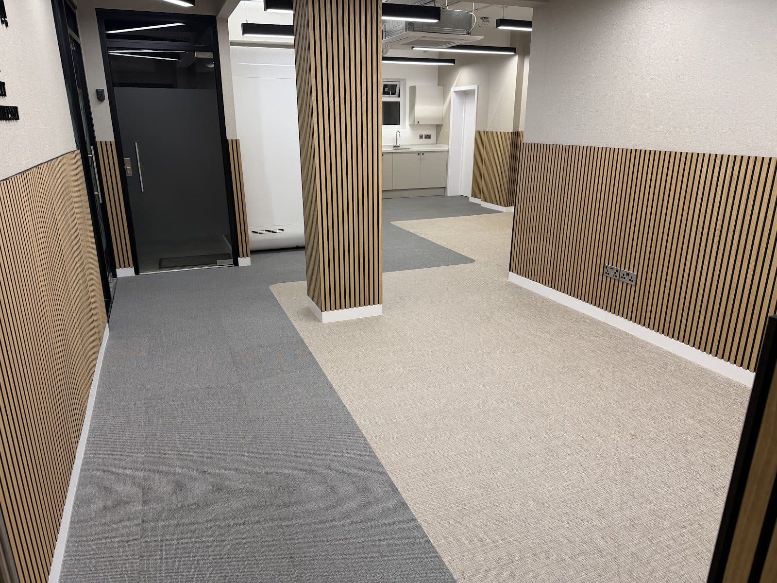 A finished office fit-out with grey carpet and slatted timber wall panels